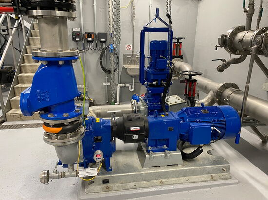 Eine blaue Industriepumpe ist in einem Technikraum auf einem Betonboden installiert.